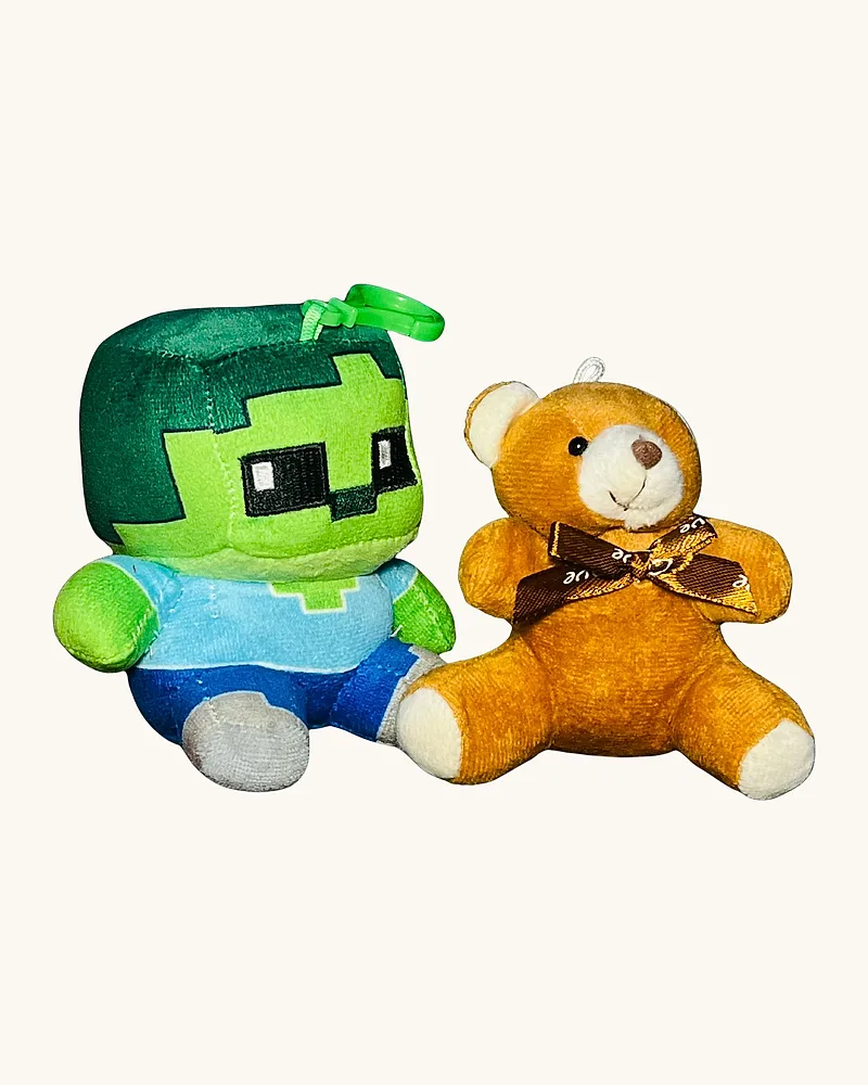 El peluche en la mano, sobre el escritorio de madera.